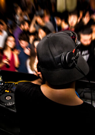 DJ with headphone and dj set at night club party. People at the