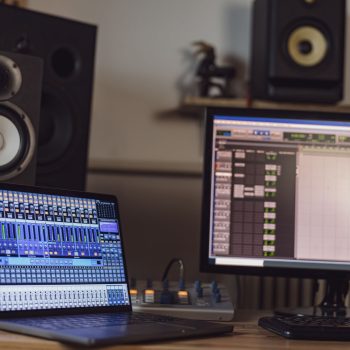 Close-up of switched on laptop and monitor screen on table in the sound engineer room in a broadcasting and recording studio